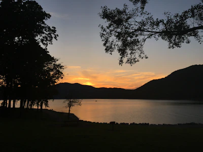 A peaceful lakeside spot reflecting the surrounding hills at sunset.