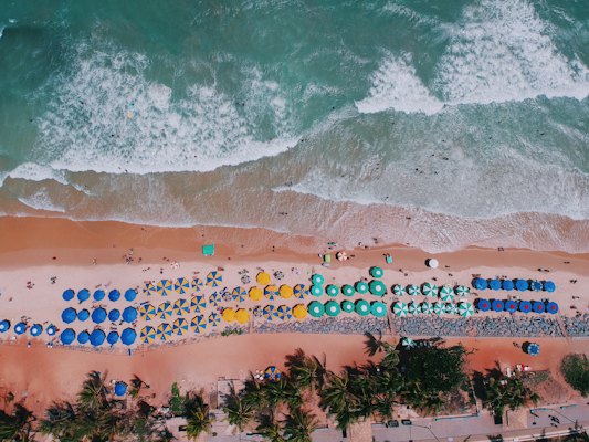 Beach umbrellas in rows on red sand, from above — Natal, Brazil