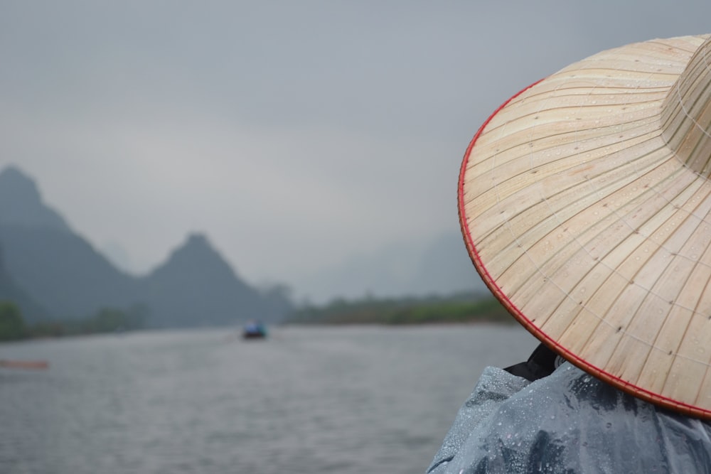 man wearing straw hat fronting body of water