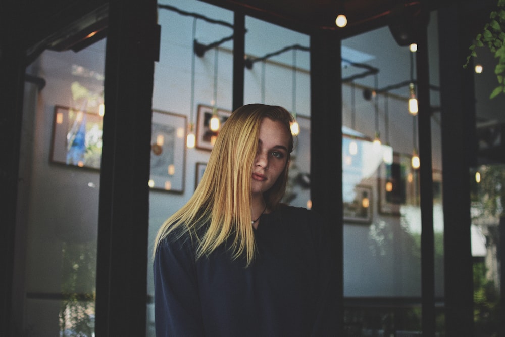 woman wearing white jacket leaning on glass wall