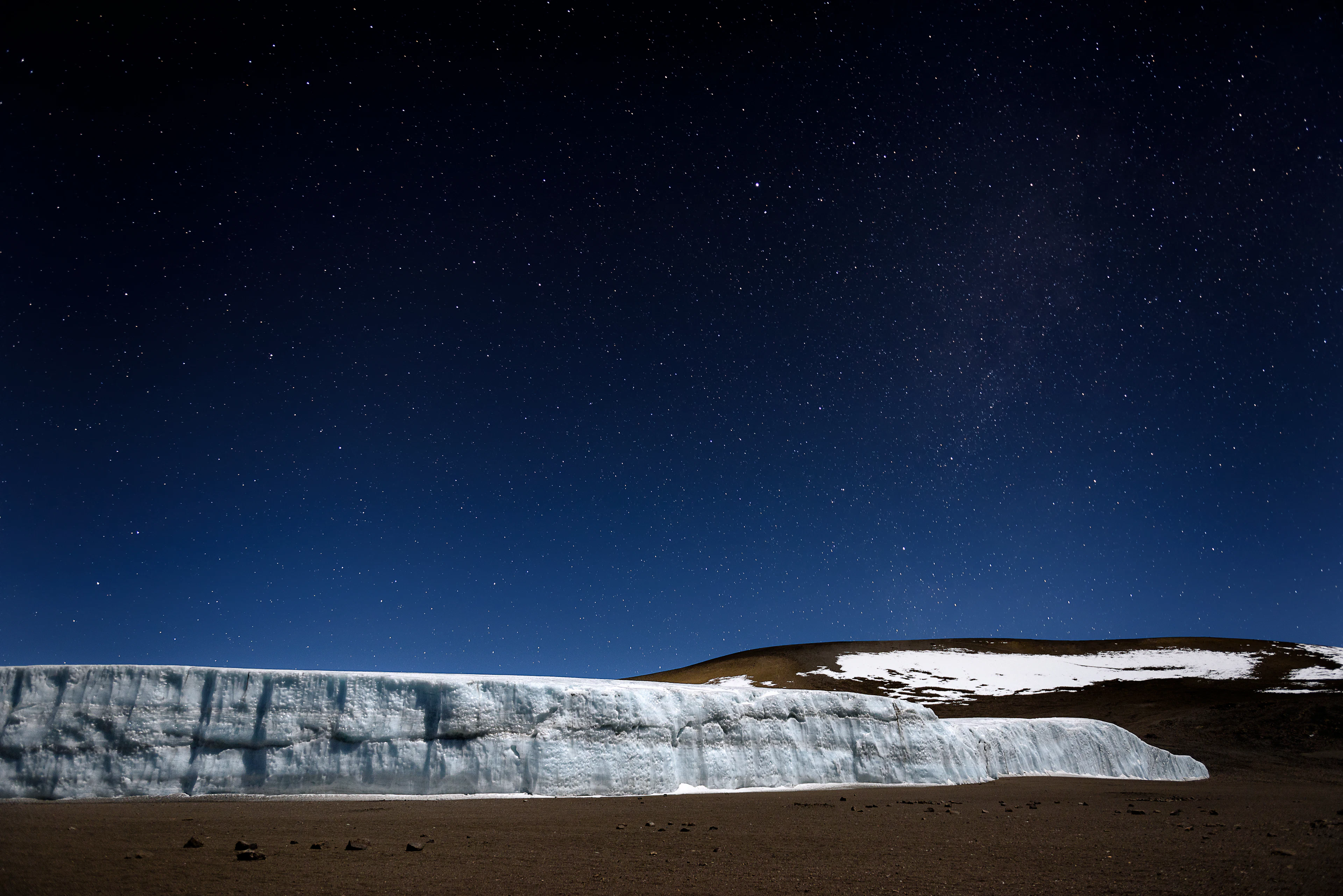 A glacier wall in Kilimanjaro's summit crater beneath a starry night sky