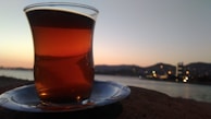 A steaming cup of herbal tea resting on a windowsill overlooking a serene pond at dusk.
