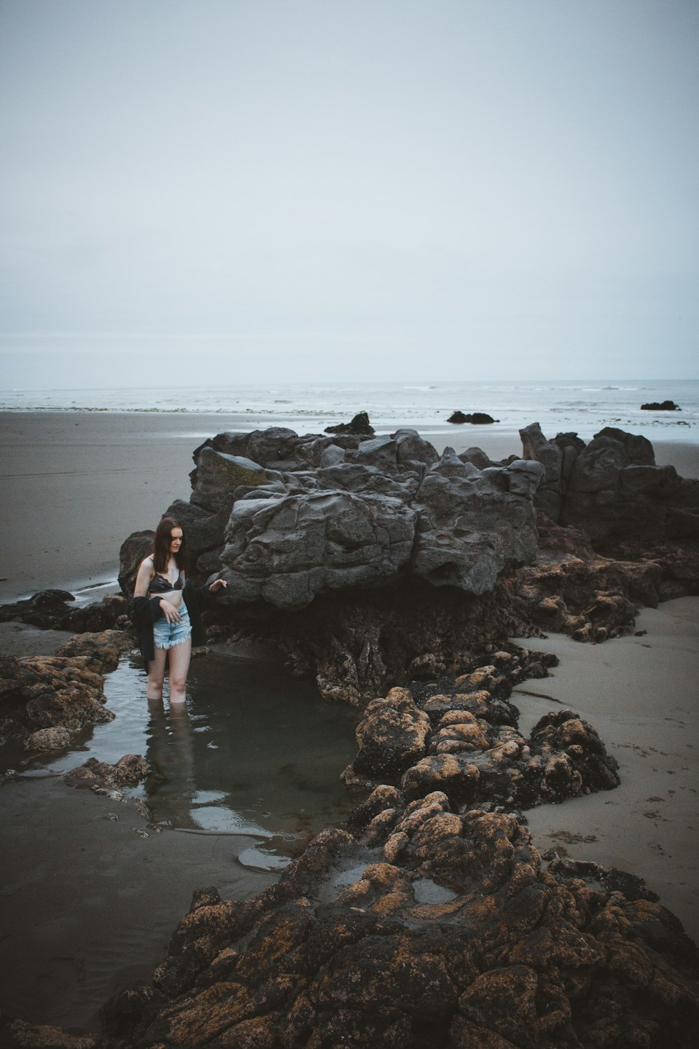 해변 해안에 돌 옆에 서있는 여자