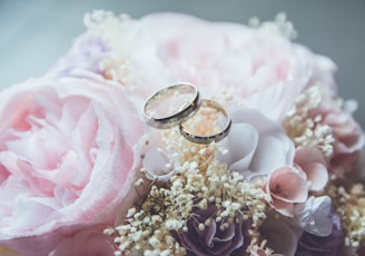 gold-colored bridal ring set on pink rose flower bouquet