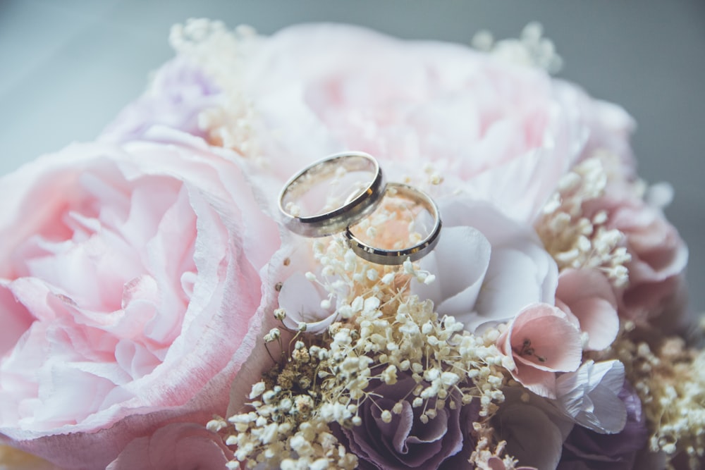 gold-colored bridal ring set on pink rose flower bouquet