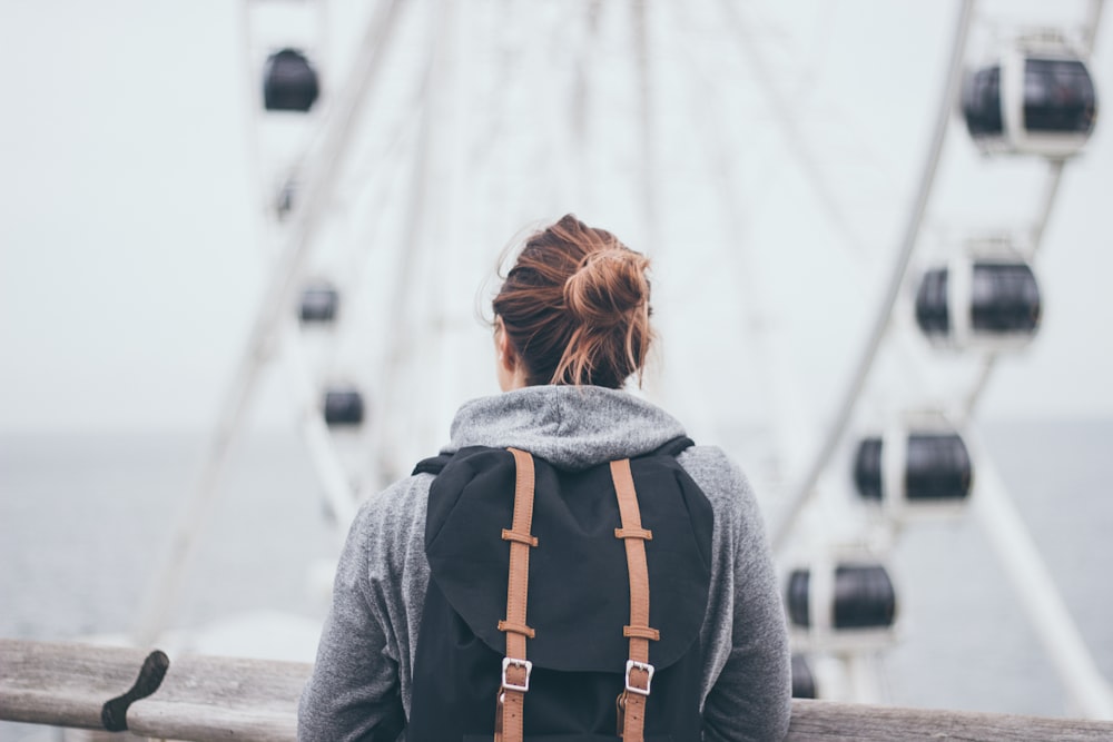 person carrying rucksack standing near rail