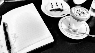 Elegant flat lay of pastries alongside a notebook and pen on cream background.