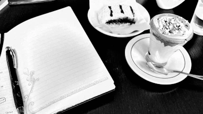 Elegant flat lay of pastries alongside a notebook and pen on cream background.
