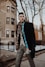 man wearing black jacket walking on sidewalk