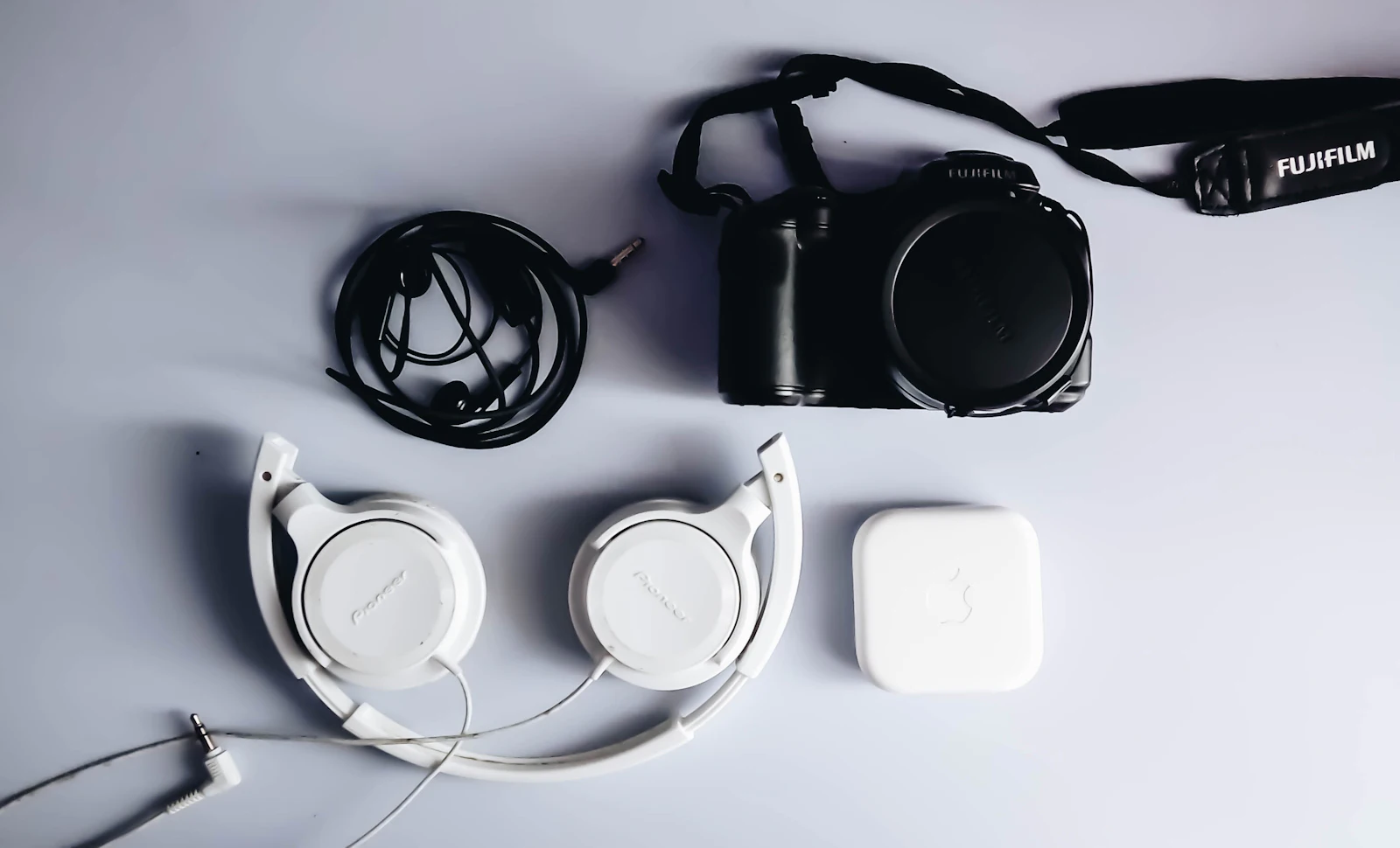 Black Fujifilm camera and white corded headphones