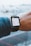 A person wearing a smartwatch that displays an electronic boarding pass. The pass shows details of a flight from Toronto Pearson International Airport (YYZ) to London Heathrow (LHR) on Air Canada. The smartwatch is on the wrist of a person wearing a denim jacket, and the background is a blurred view of an airport with airplanes.