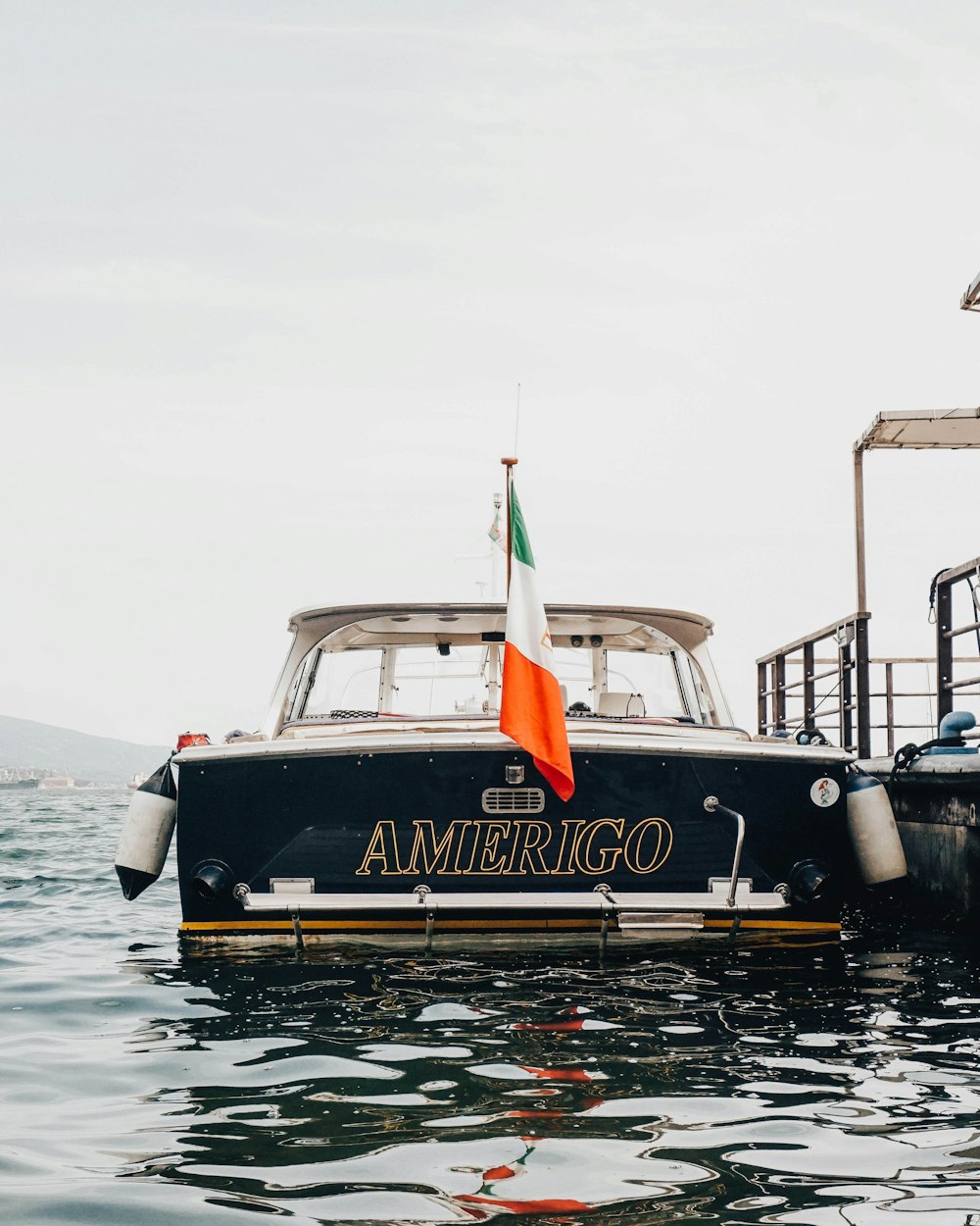 black and white Amerigo boat beside gray concrete dock during daytime