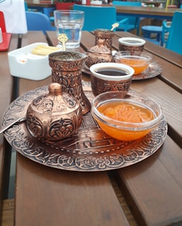 A beautifully arranged traditional Arabic coffee set with ornate cups and a dallah on a wooden table.
