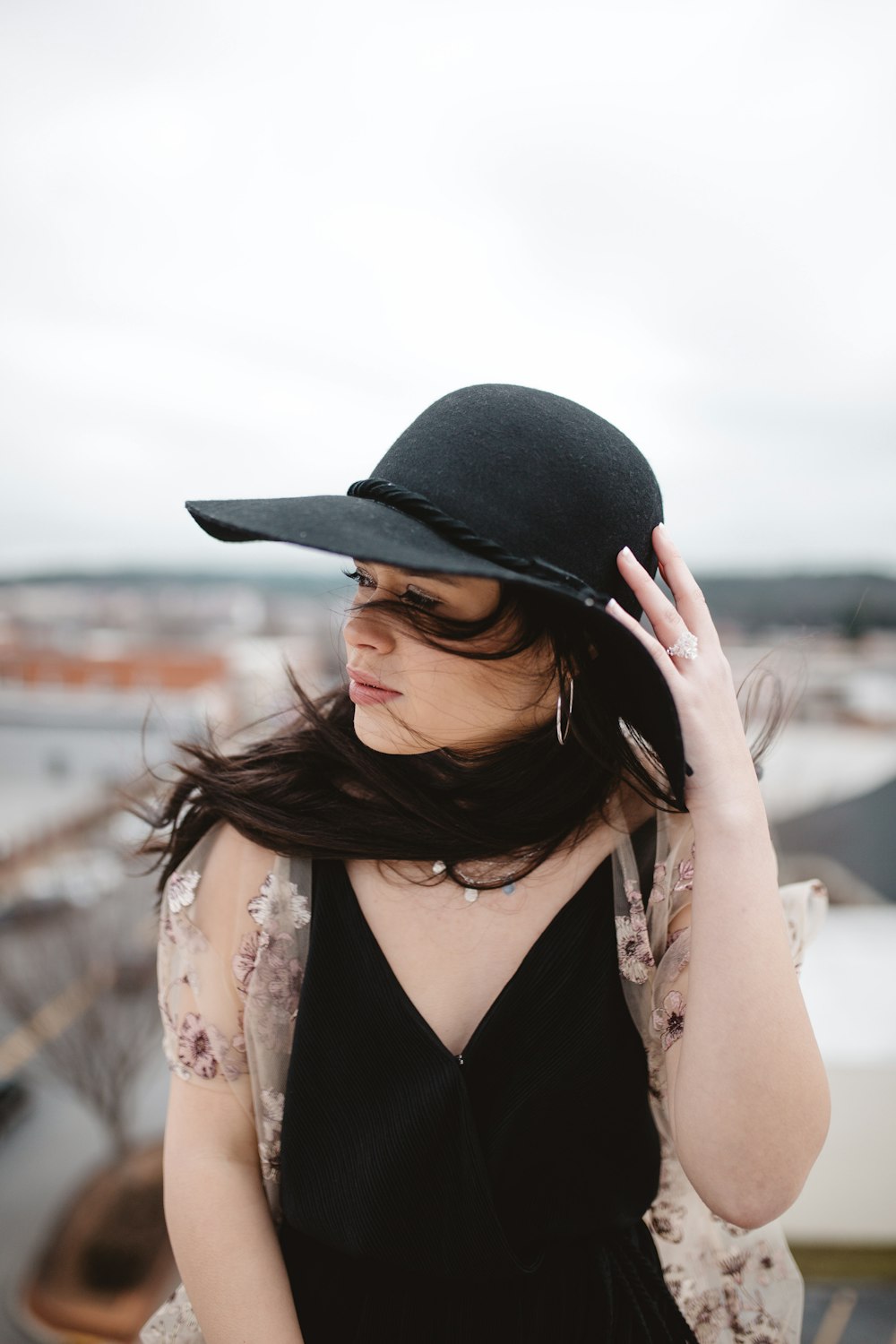 woman holding her hat while being blown by wind