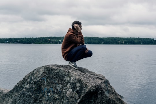 man wearing brown hoodie while standing on rock in Vyborg Russia