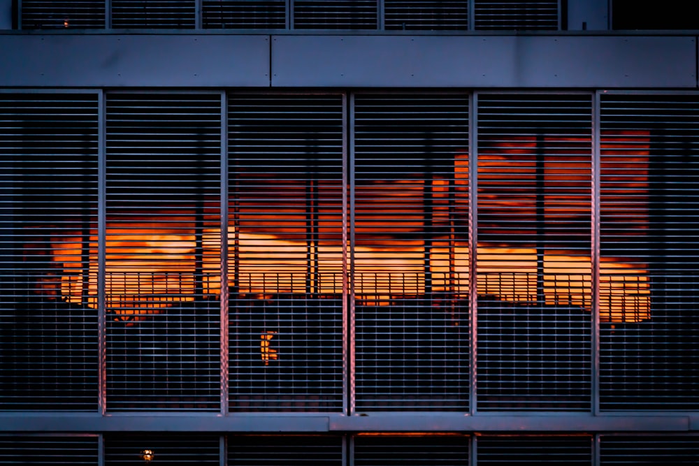 o sol está se pondo atrás das persianas de um prédio