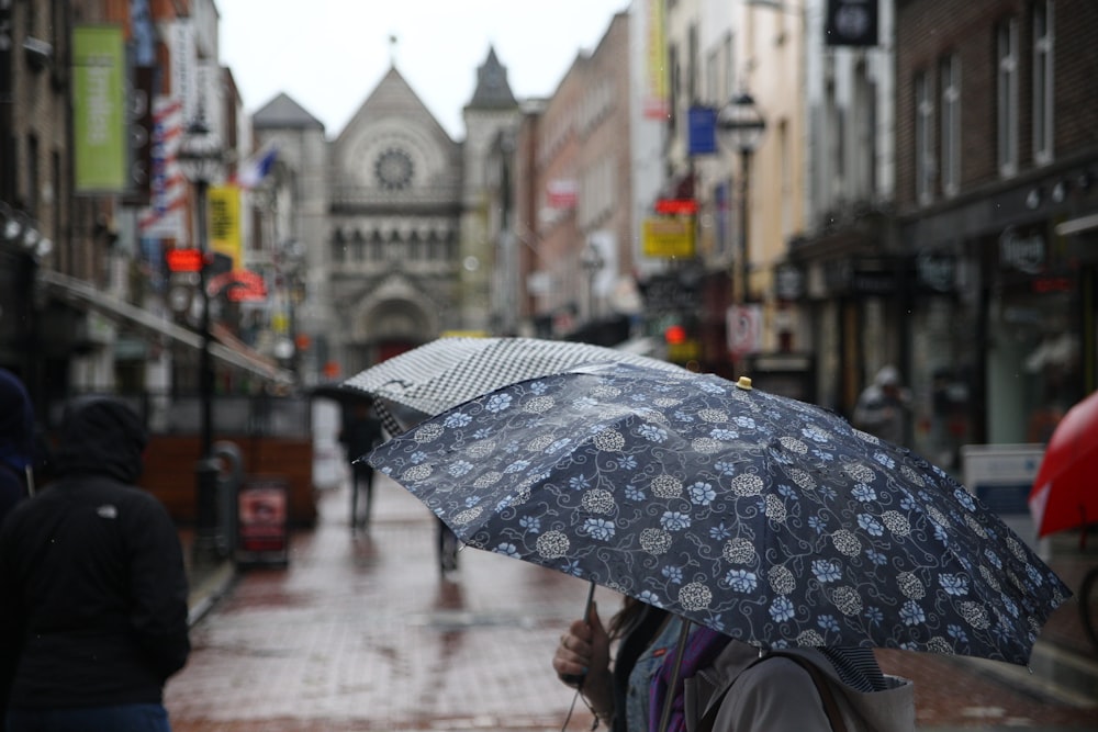 Persona sosteniendo un paraguas floral entre edificios