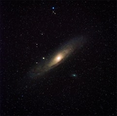A spiral galaxy surrounded by a multitude of stars. The galaxy has a bright core with spiral arms extending outward, giving it an elliptical appearance.
