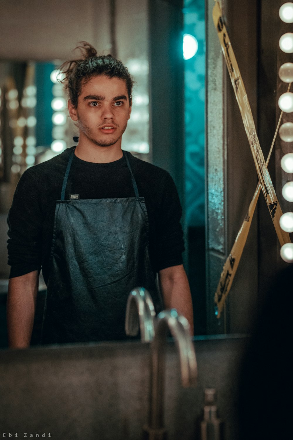 photo of man looking at mirror wearing black apron