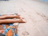Sun-kissed legs resting on a neutral-toned towel after a tanning session.