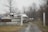 Several boats are parked on a rainy or foggy day behind a wooden fence, with a sign reading 'GOOD BOATS FOR SALE'. The scene is set against a backdrop of leafless trees, suggesting late autumn or winter.