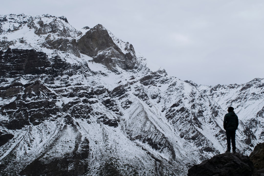 silhouette photography of person standing on mountain under white sky