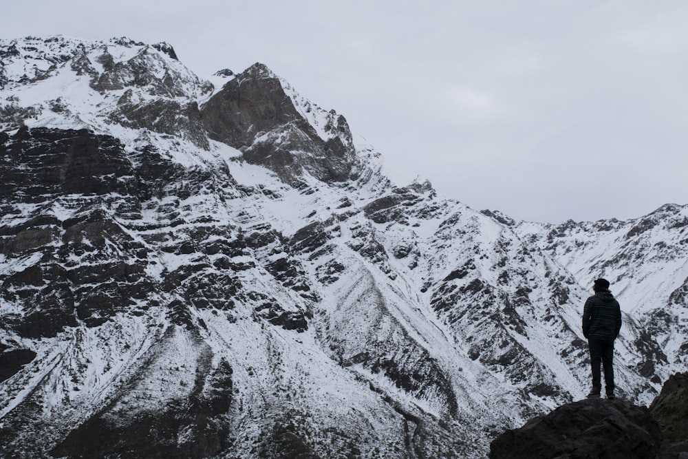 Silhouettenfotografie einer Person, die auf dem Berg unter weißem Himmel steht