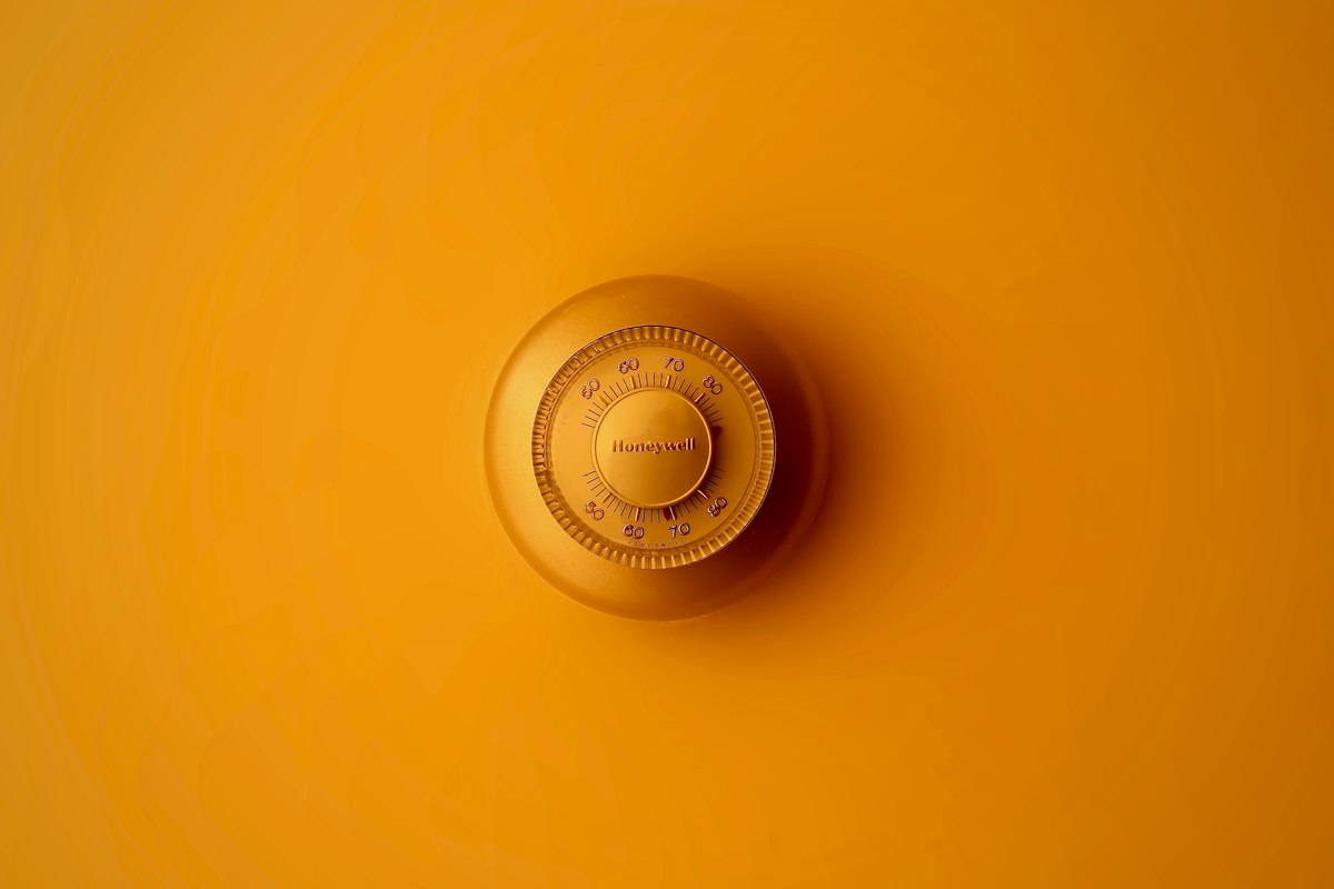 Wall-mounted round home thermostat dial in warm orange tones