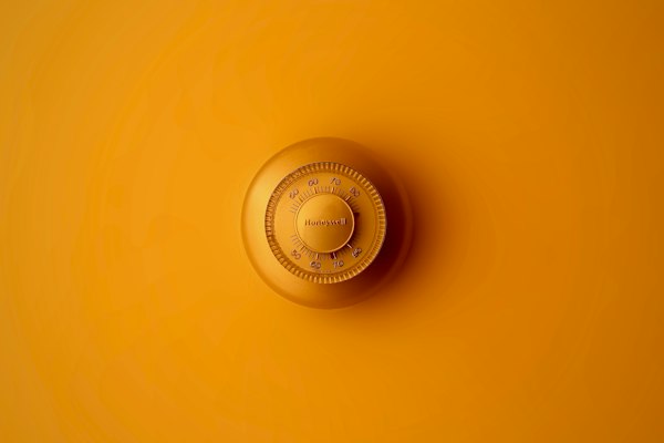 Wall-mounted round home thermostat dial in warm orange tones