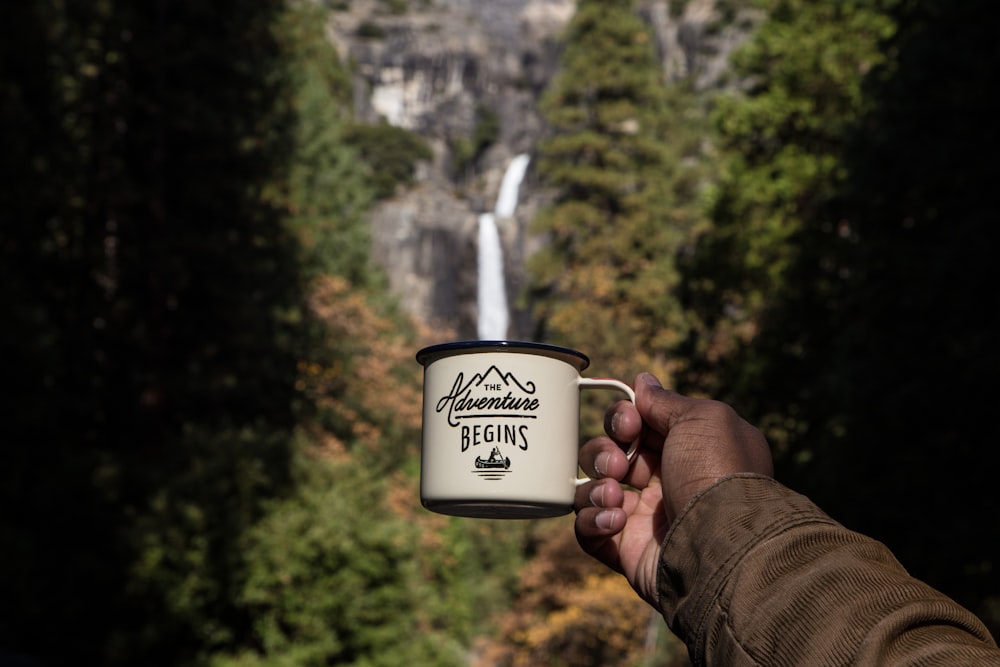 person holding white and brown mug