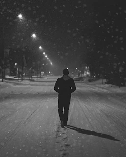 A shadowy figure walking through a snowy street outside a warmly lit church window, embodying the Five of Pentacles tarot card's themes of hardship and hope.