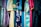 A variety of colorful fabrics and garments hang together, showcasing intricate patterns and a mix of textures. The textiles include floral designs, geometric patterns, and embroidery, featuring shades of blue, pink, gold, and teal.
