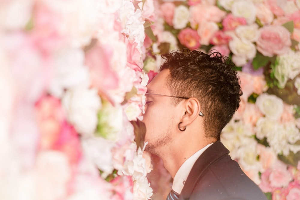 man leaning on flower wall