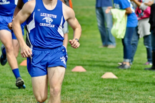 man in blue Champion tank top and shorts running at the field in Lexington United States