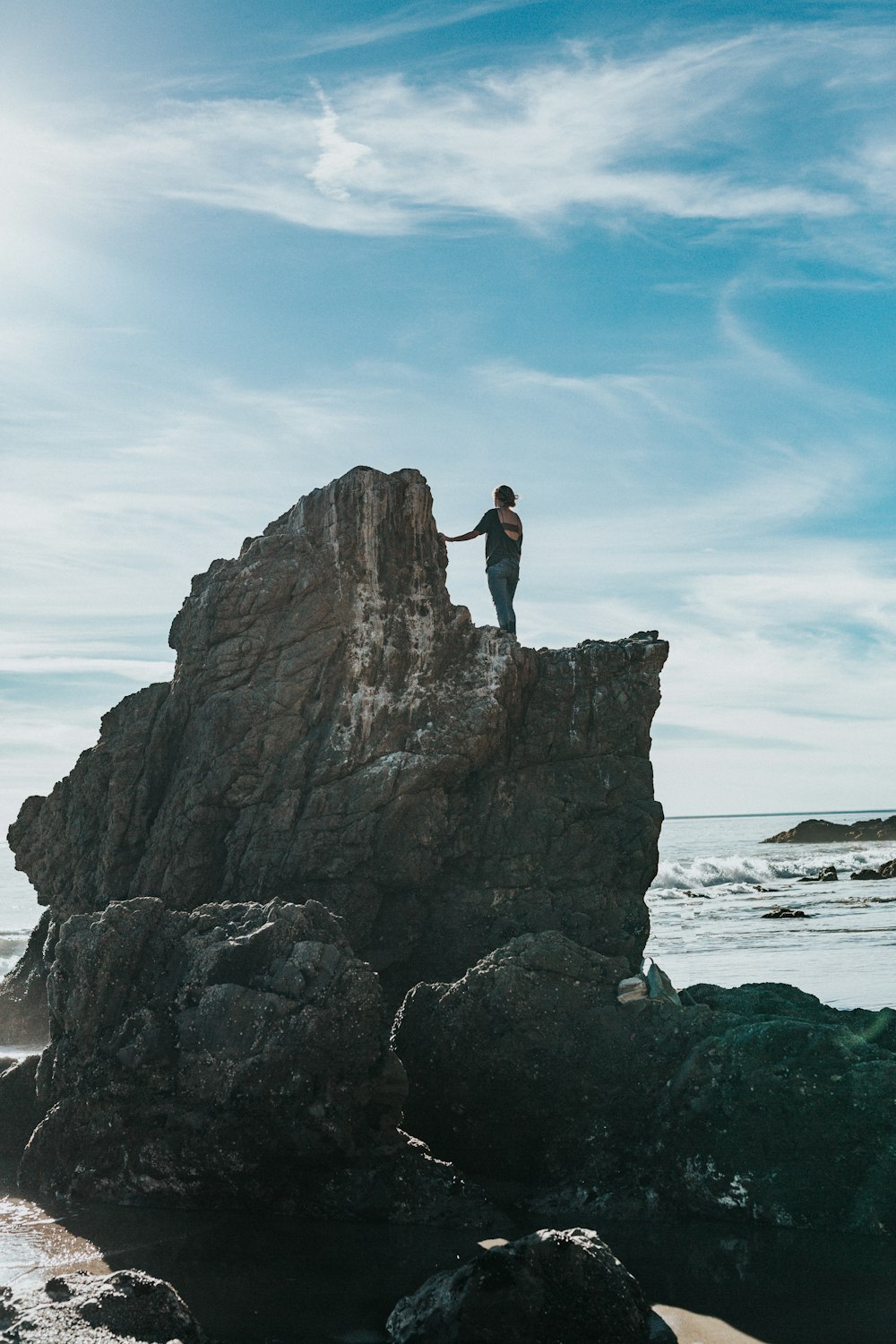 woman standing on top of gray rock formation