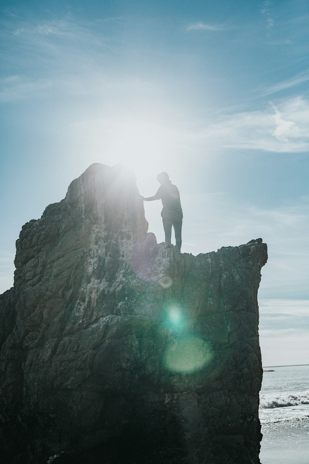 silhouette of person standing on gray rock formation