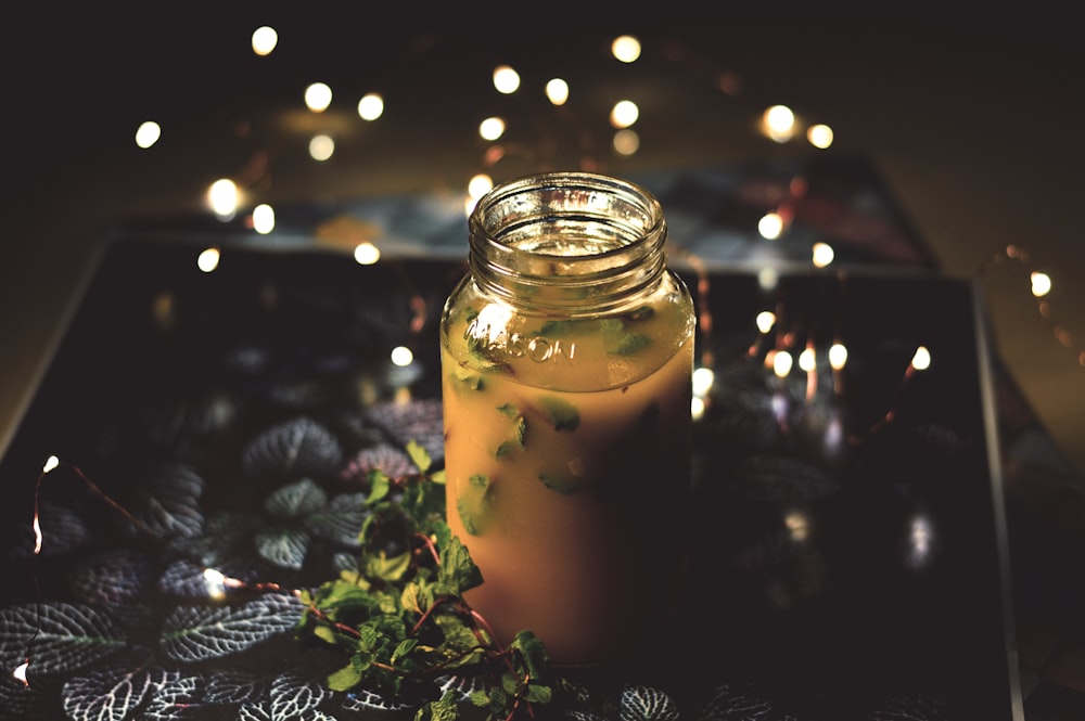 jar filled with brown liquid with leaves on tray