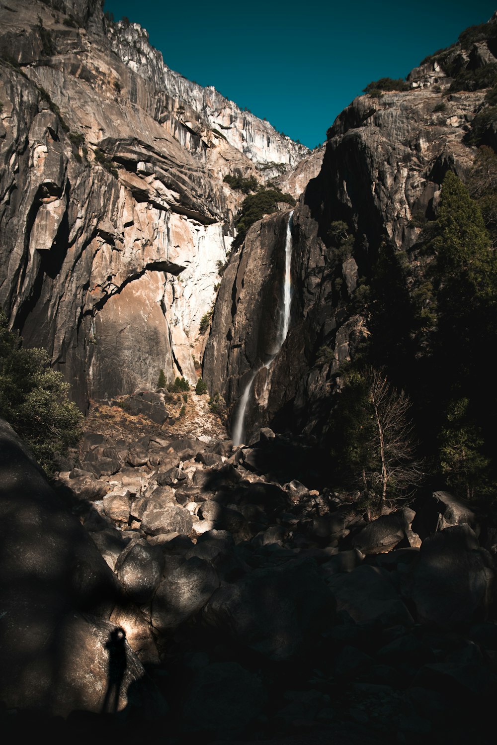 昼間は青空の下、岩山に囲まれた滝