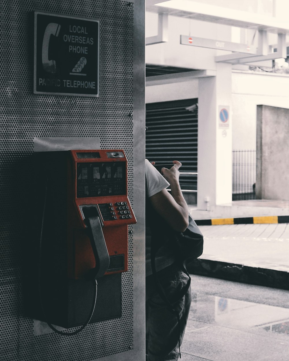 person leaning on wall near brown payphone