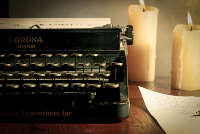 An old, weathered typewriter with a half-finished manuscript titled 'The Crimson' resting beside a flickering candle.