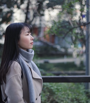 woman in gray scarf and coat standing near bridge