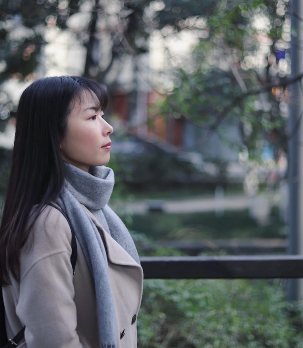 woman in gray scarf and coat standing near bridge