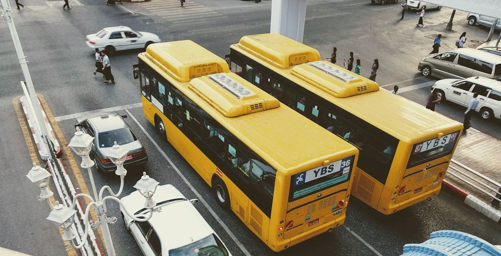 two buses beside white cars