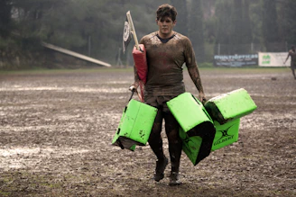 man covered in mud carrying leather training pads
