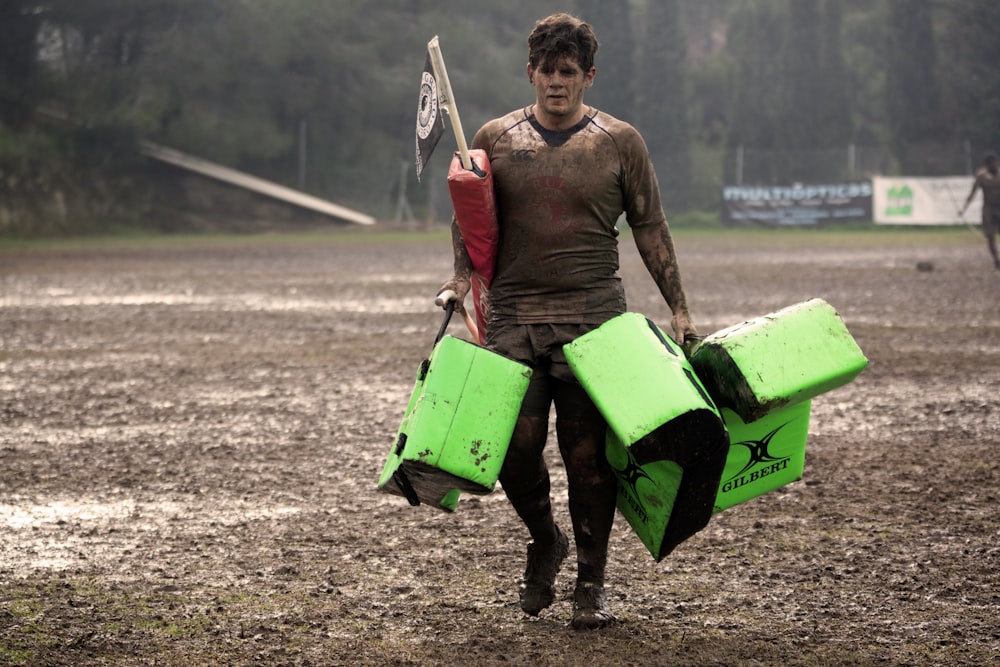 man covered in mud carrying leather training pads