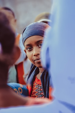selective focus photo of child in red top and black headscarf