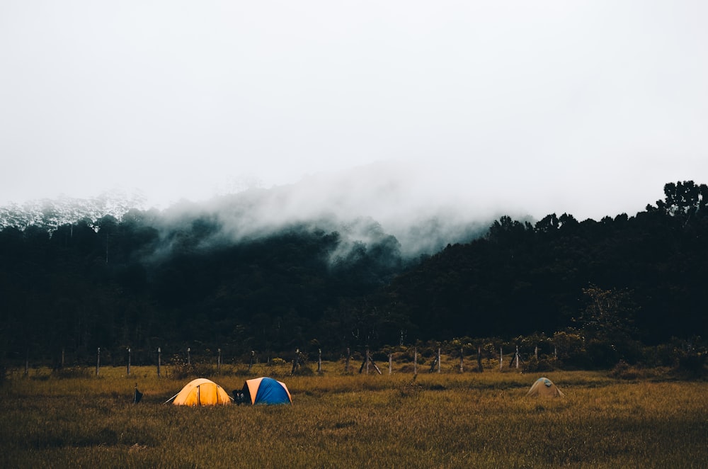 Deux tentes dôme bleues et jaunes sur le sol près de la montagne avec de la fumée