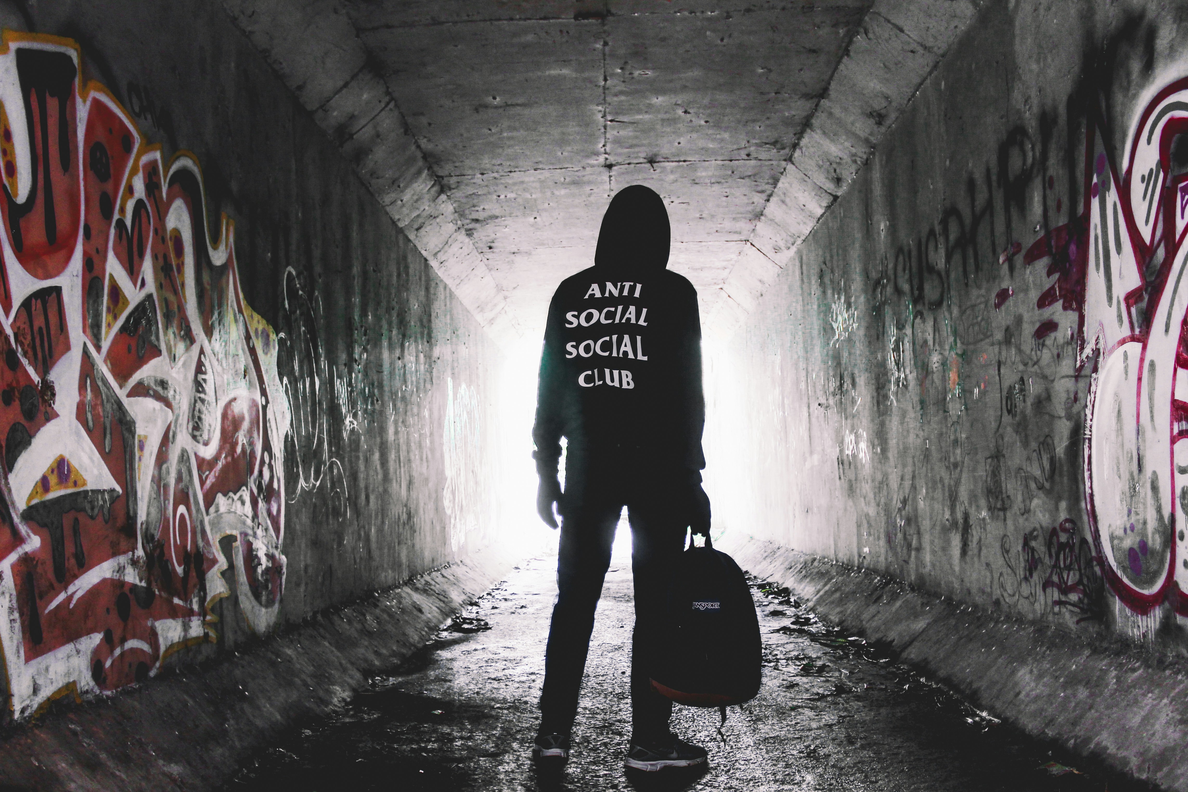 person holding bag standing inside tunnel