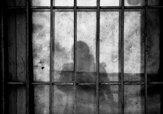 a shadow of a person behind bars in a jail cell