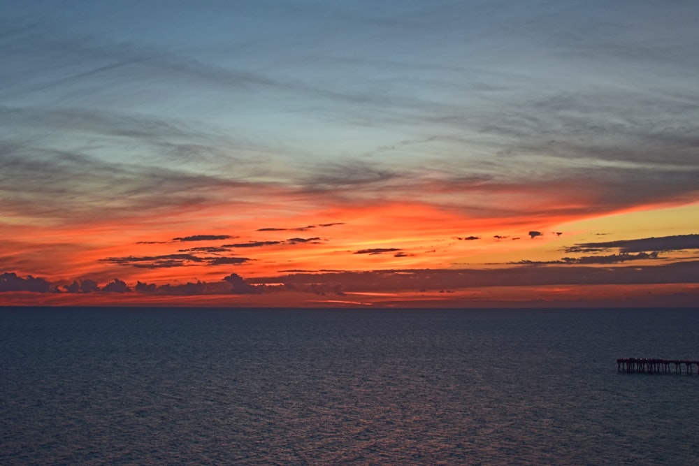 body of water under orange and white sky